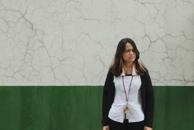 Portrait of a beautiful young woman standing against wall