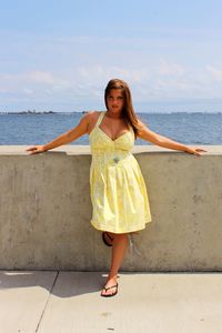 Portrait of young woman standing against sea