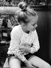 Girl looking away while sitting outdoors