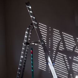 Low angle view of illuminated lighting equipment against wall