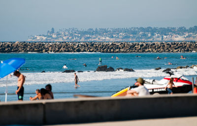 People at beach against clear sky