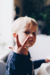 Close-up portrait of cute boy showing peace sign