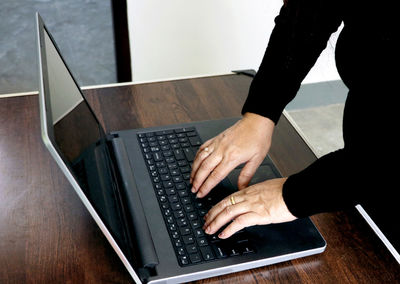 Cropped hands using laptop on table