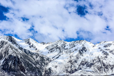 Low angle view of snowcapped mountains against blue sky