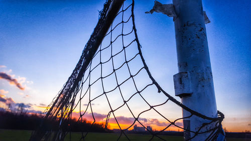 Low angle view of net on field against sky during sunset