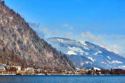 Scenic view of sea by mountain against sky