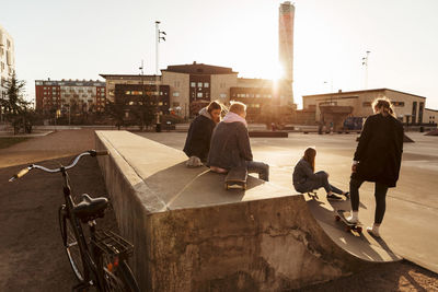 Friends hanging out at skateboard park in city during sunny day