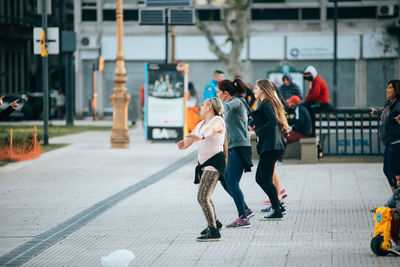 Rear view of people walking on street in city