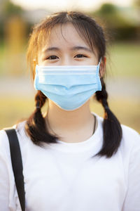 Portrait of teenage girl wearing mask standing outdoors