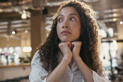 Thoughtful businesswoman sitting with hands on chin in office