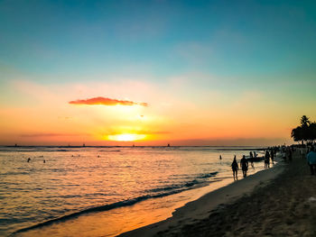 Silhouette people on beach against sky during sunset