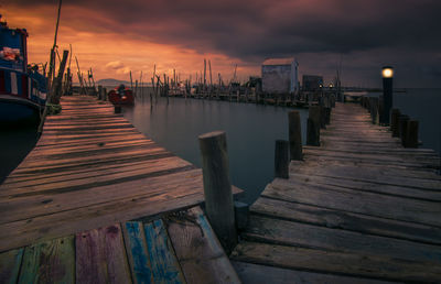 Wooden jetty in sea at sunset