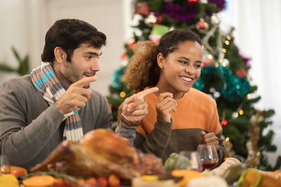 Man and woman sitting by christmas tree