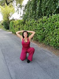 Portrait of woman sitting on road against plants