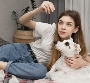Girl playing with dog on bed at home