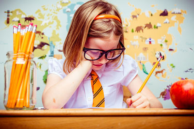 Girl writing while sitting at desk in school