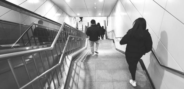 Rear view of people walking on escalator