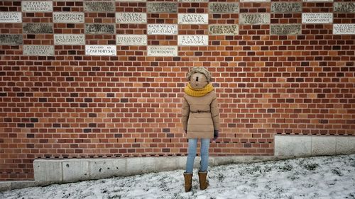 Rear view of girl looking at text on brick wall