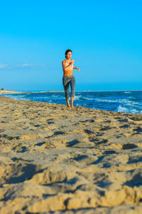 Full length of man standing on beach against sky