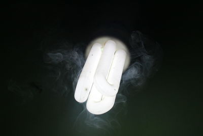 Close-up of illuminated light bulb over black background