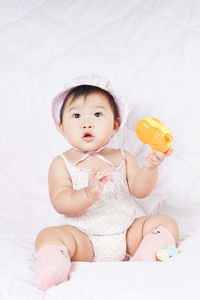 Cute baby girl sitting on bed at home