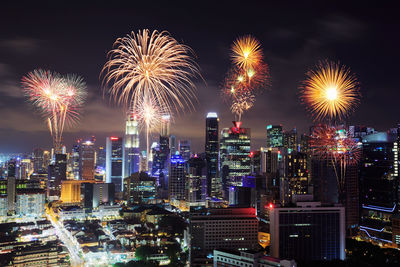 Firework display over illuminated buildings in city at night