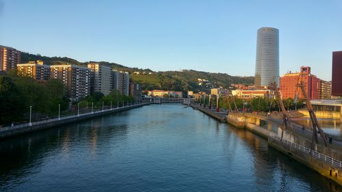 Bridge over river in city against clear sky