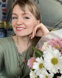 Portrait of smiling young woman holding flowers