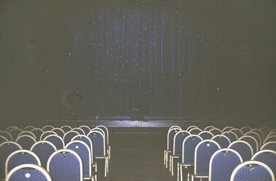 Empty chairs against wall at night