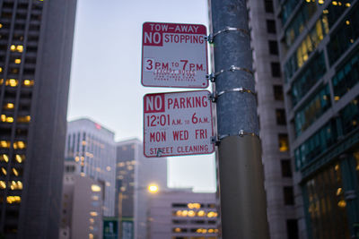 Low angle view of information signs on pole in city at dusk