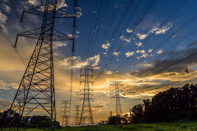 Low angle view of electricity pylon on field against sky