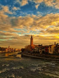 River in city against sky during sunset