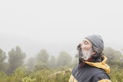 Relaxed mountaineer breathing fresh air high in the mountains with fog in the background