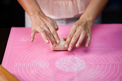 Cropped hands of woman making heart shape on table