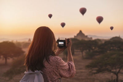 Rear view of woman photographing at sunset