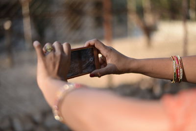 Cropped hands of woman photographing with mobile phone outdoors