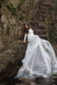Bride wearing white wedding dress sitting on rocks