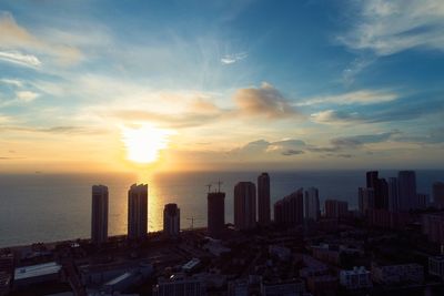 Modern buildings in city against sky during sunset