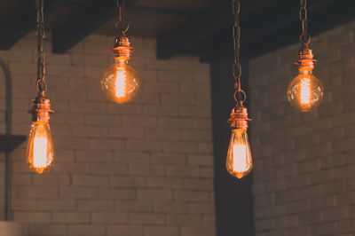 Low angle view of illuminated light bulbs hanging in row
