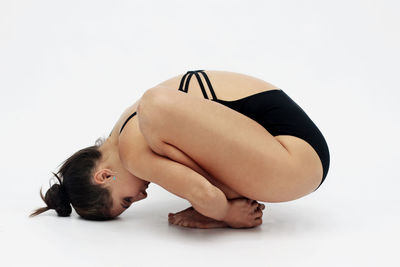Young woman practicing yoga against white background