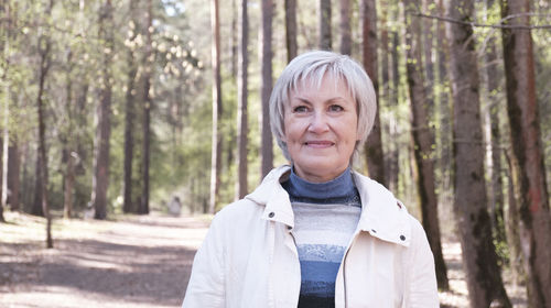 Portrait of woman standing against trees in forest