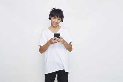 Full length of smiling young man using mobile phone