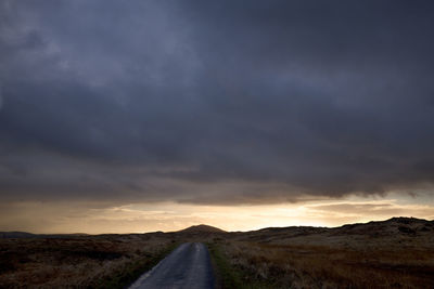 Country road against cloudy sky