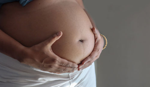 Close-up of woman touching face against black background