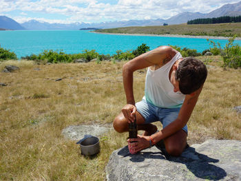 Man preparing food on rock against sky