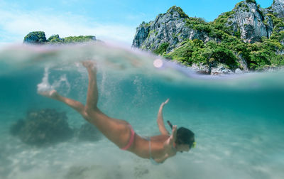 Woman snorkeling in sea against mountain