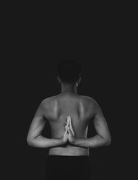 Shirtless man standing against black background