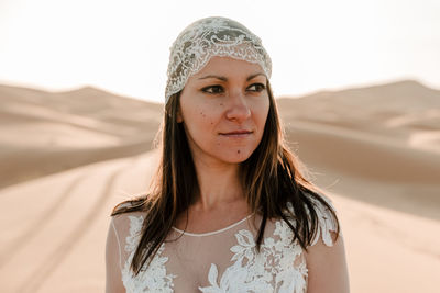 A young brunette in her wedding dress and wedding veil in the desert as the sun rises 