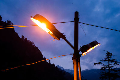 Low angle view of electricity pylon against sky during sunset