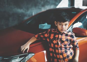 Boy standing against car